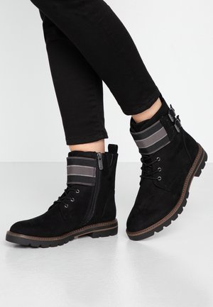Bottines en daim noir avec un revers en tissu rayé, lacées à l'avant, avec une fermeture éclair sur le côté et une semelle en caoutchouc texturée. Convient pour une tenue décontractée.