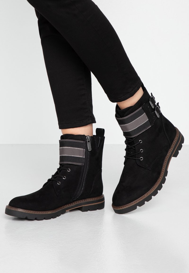 Stivali alla caviglia in suede nero con un risvolto in tessuto a righe, chiusura con lacci sul davanti, zip laterale e suola in gomma texturizzata. Ideali per un look informale.