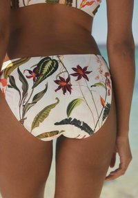 Zwemonderdelen met een bloemenpatroon, versierd met rode bloemen en groene bladeren op een witte achtergrond, gemaakt van een zachte, rekbare stof.
