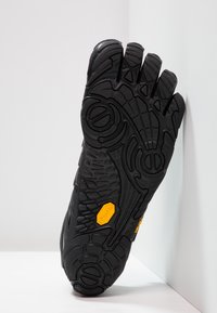 Czarny but z oddzielonym palcem, z teksturowaną gumową podeszwą, z wyraźnym żółtym logo Vibram i charakterystycznym wzorem bieżnika zapewniającym przyczepność.