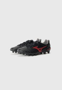 Black soccer cleats with red accents, made of synthetic material. Features a textured upper with ridges and molded studs for traction.