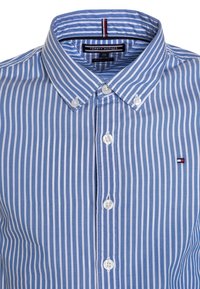 Blauw-wit gestreepte shirt met een button-down kraag, voorzien van een logo aan de linkerkant en witte knopen. Gemaakt van biologisch katoen.