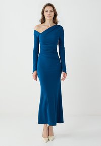 Robe longue ajustée en tissu bleu. Présente un design d�énudé d'épaules, des manches longues et des détails froncés à la taille. Texture lisse.