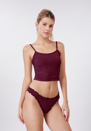 Μπορντό κοντό τοπ με λεπτές τιράντες και στρογγυλή λαιμόκοψη, συνδυασμένο με ταιριαστά μαγιό σλιπ με βολάν και μαύρο περιθώριο.