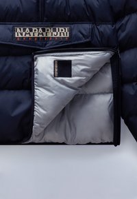 Giubbotto imbottito blu navy con rivestimento argento e patch interno con marchio. Presenta un design spesso a quadretti e una chiusura con zip robusta.