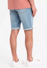 Ljusblå denimshorts med slitna detaljer och uppvikta muddar. Stylade med vita sneakers, vilket ger en avslappnad och ledig look.