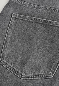 Denim tkanina u izblijedjeloj sivoj boji ima jedan stražnji džep s čistim šavovima i suptilnom teksturom. Ukupno, klasičan dizajn.