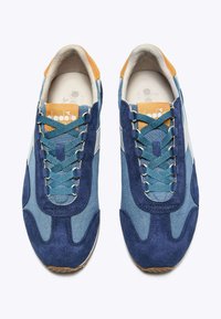 Sneaker blu navy e azzurro chiaro con materiali in camoscio e tessuto, caratterizzati da dettagli marroni, lacci grigi e una suola in gomma texturizzata.