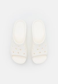 Sandales en mousse blanches avec des trous de ventilation, bout ouvert et texture lisse. Design simple avec une semelle plate. Convient pour un usage décontracté.