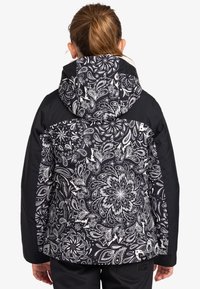Schwarz-weiße gemusterte Jacke mit floralem Design, ausgestattet mit einer Kapuze und kontrastierenden einfarbigen schwarzen Einsätzen an den Schultern und Ärmeln.