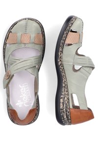 Sandales en cuir vert avec des accents marron, design découpé et brides réglables. Semelle texturée avec un motif tacheté contrasté.