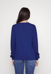 Long-sleeve top with blue and black striped pattern, round neckline, and gathered details at the sleeve cuffs, made from a soft fabric.