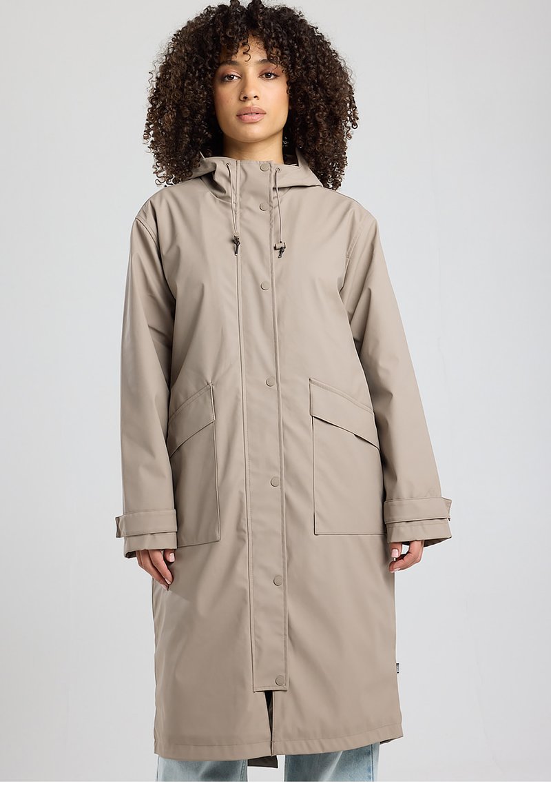 Manteau imperméable beige avec capuche à cordon de serrage, boutons-pression et grandes poches avant. Coupe décontractée et longueur jusqu'aux genoux.