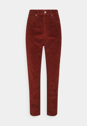Pantalon en velours côtelé rouge rouille à taille haute avec poches avant, passants pour ceinture, fermeture par bouton, et jambes slim fuselées.