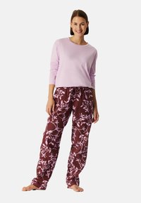 Licht paarse lange mouwen top gecombineerd met kastanjebruine broek met een roze bloemenpatroon. Beide zijn gemaakt van zachte, comfortabele stof.
