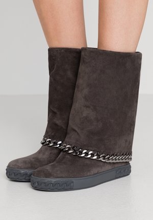 Miękkie, ciemnoszare zamszowe kozaki do połowy łydki z płaskimi gumowymi podeszwami i srebrnym łańcuszkiem wokół przedniej części kostki.