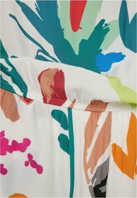 Tissu avec imprimé floral abstrait multicolore comprenant des formes bleu sarcelle, rouge, bleu, rose, orange et beige sur fond blanc avec couture froncée.