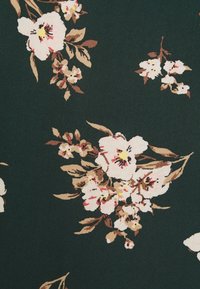 Tissu vert foncé avec des grappes éparses de motifs floraux beiges, blancs et roses, accompagnés de feuilles marron.