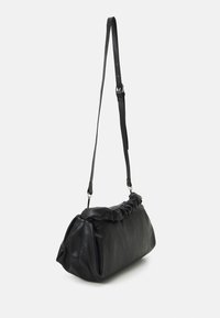 Musta nahkainen olkalaukku, jossa on rypytetty yläosa, säädettävä olkahihna ja pehmeä, pyöreä muoto. Sileä koostumus ja hillityt metallikoristeet.