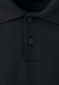 Polo negro con cuello acanalado, tapeta de tres botones y una textura suave. La tela parece blanda y ligera.
