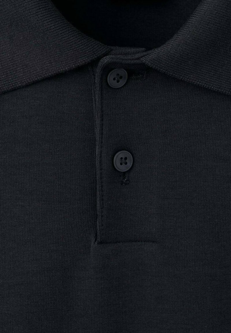 Un polo noir avec un col côtelé, une patte de boutonnage à trois boutons et une texture lisse. Le tissu semble doux et léger.