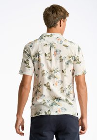 Camicia a maniche corte di colore chiaro con motivo floreale, caratterizzata da foglie verdi e fiori arancioni, realizzata in un tessuto testurizzato e traspirante.