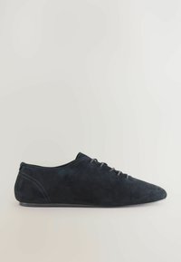 Scarpa in suede nera con un profilo basso, punta rotonda e lacci sottili. Presenta una texture liscia e un design minimalista.