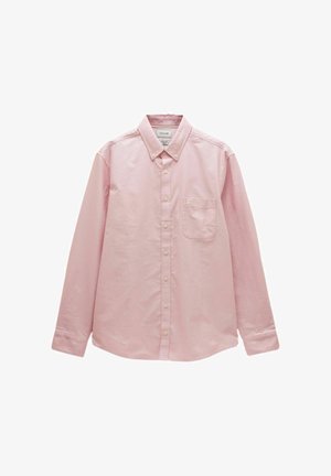 Person, die die Manschette eines hochgekrempelten, hellrosa Langarmhemds mit einem aufgenähten "My Shirt"-Etikett anpasst.