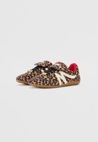 Leopard print athletic shoes with a textured upper, white accents, adjustable Velcro straps, and a rubber outsole. Red lining visible inside.