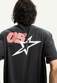 T-shirt in cotone nero con una grande grafica rossa "05" e una stella bianca sul retro, maniche corte e vestibilità rilassata.