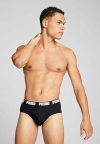 Black brief underwear with a white "PUMA" logo on the waistband, fitted design, smooth fabric, and a classic athletic cut.