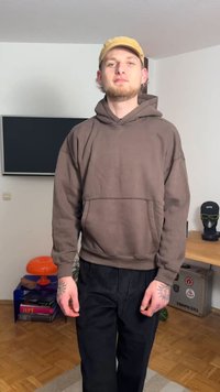 Brun pullover-hoodie med känguruficka, strukturerat tyg och ledig passform. Matchas med svarta manchesterbyxor. Minimalistisk design.