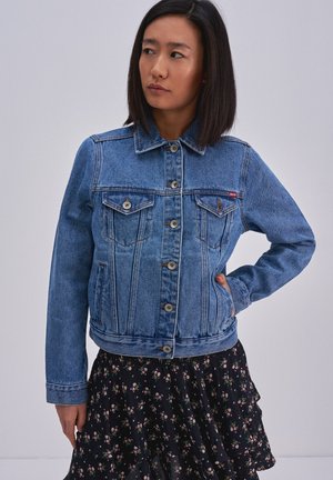 Giacca di denim in azzurro chiaro, con chiusura frontale a bottoni, due tasche sul petto e un lunghezza leggermente accorciata. Cuciture semplici e colletto classico.