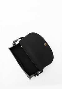 Black leather handbag with a curved flap, gold hardware, and a single detachable strap. Interior is lined, offering a spacious main compartment.