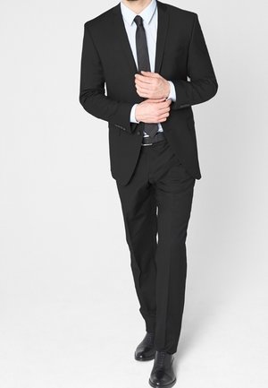Black suit with a slim fit, matching tie, white dress shirt, and black shoes. Smooth fabric, tailored shape, and minimal embellishments.
