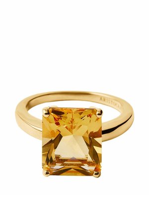 Anillo de oro con una gran piedra preciosa amarilla de corte cuadrado, montada en una engaste de cuatro puntas sobre una banda lisa y pulida.