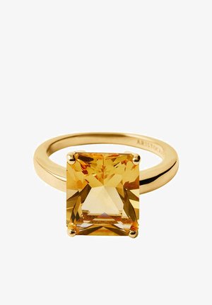 Anillo de oro con una gran piedra preciosa amarilla de corte cuadrado, montada en una engaste de cuatro puntas sobre una banda lisa y pulida.