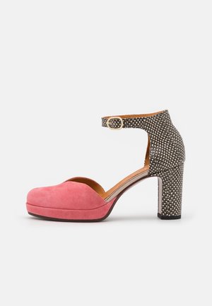Pink suede platform pump with a black and white polka dot ankle strap and a chunky heel. Features a rounded toe and a smooth interior.
