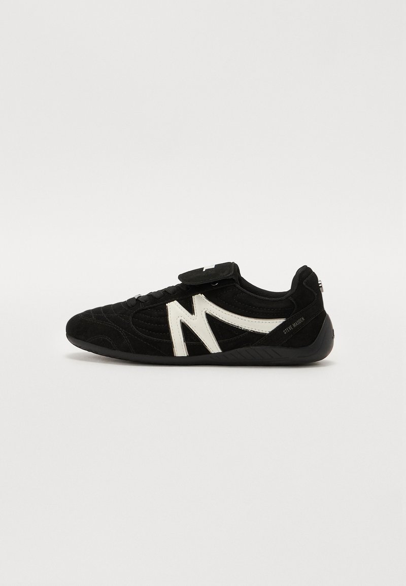 Shoe de camurça preta com um design distinto em branco. Apresenta um bico arredondado, parte superior texturizada, fecho de atacadores e uma tira de Velcro.