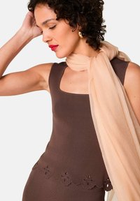 Bruine mouwloze top met een vierkante halslijn en bloemenborduursel, gecombineerd met een lichtbeige sjaal met een zachte, sheer textuur.