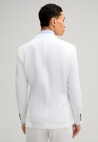 Weißer Blazer mit einer glatten Textur, einzelnem Rückenschlitz, taillierter Passform und blauen Akzenten am Kragen. Knopfdetails an den Ärmeln.