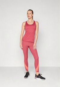 Bordó sportos ujjatlan felső és leggings narancssárga díszítéssel, rugalmas anyagból készült. A szettet fekete futócipő egészíti ki.