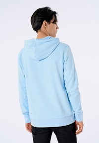 Felpa blu chiaro realizzata in tessuto morbido, con cappuccio regolabile, polsini e orlo a costine, dal fit rilassato.