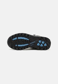 Black outdoor shoe sole with a rugged tread pattern; features blue accents and branding "Columbia" on the side, designed for grip and traction.