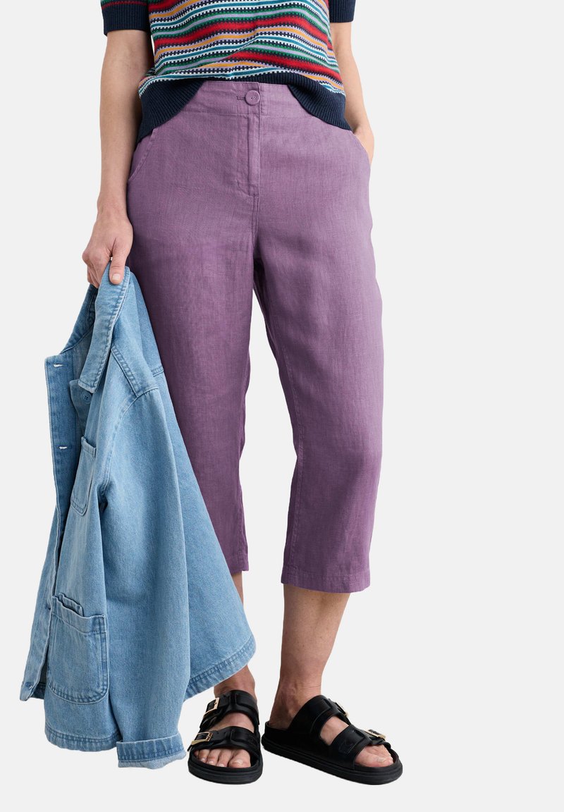 Lila lanena kratka hlače z gumbom in stranskimi žepi, kombinirane s svetlo modrim denim jopičem in črnimi sandali.