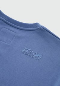 Niebieski sweatshirt z okrągłym dekoltem, prążkowanymi mankietami i teksturowanym nadrukiem na plecach, który brzmi "NIE MA NIC ZŁEGO W NIE MIEĆ PLANU". Miękka tkanina.