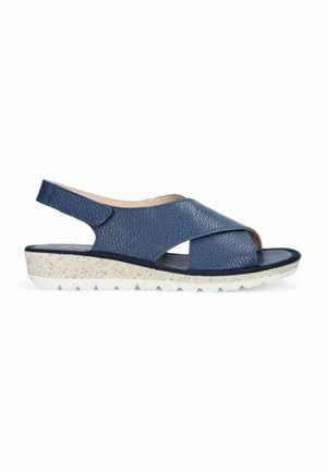 Sandalias de cuero azul marino con tiras cruzadas, talonera y suela blanca moteada con un acabado texturizado.