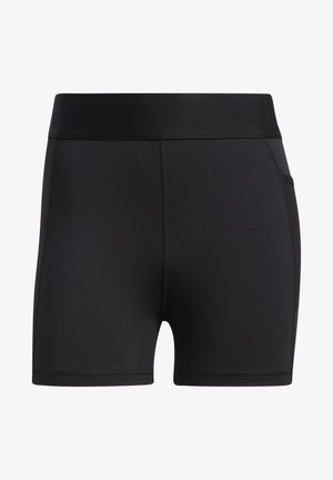 Kobieta nosząca czarny sportowy biustonosz, czarną bluzę z kapturem na zamek, czarne spodenki rowerowe i czarne sneakersy Adidas, pokazana od ramion do stóp.