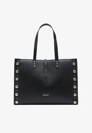 Sac cabas en cuir noir à la forme structurée, orné de clous argentés sur un côté, avec des accents métalliques et un détail de fermeture à l'avant.