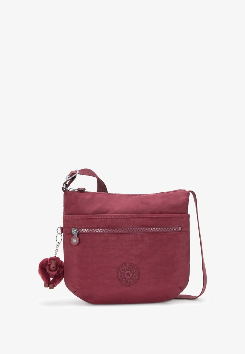 Petit sac bandoulière bordeaux avec poche avant zippée, sangle réglable et un porte-clés singe en peluche attaché à la tirette du zip.